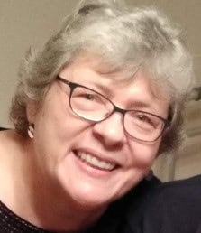 Smiling older woman with short gray hair and glasses