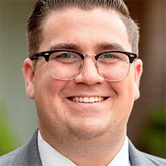 Portrait of a smiling man wearing glasses and a suit jacket