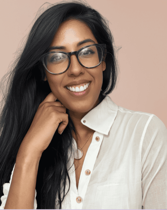 Portrait of a smiling woman with long dark hair and glasses wearing a white shirt