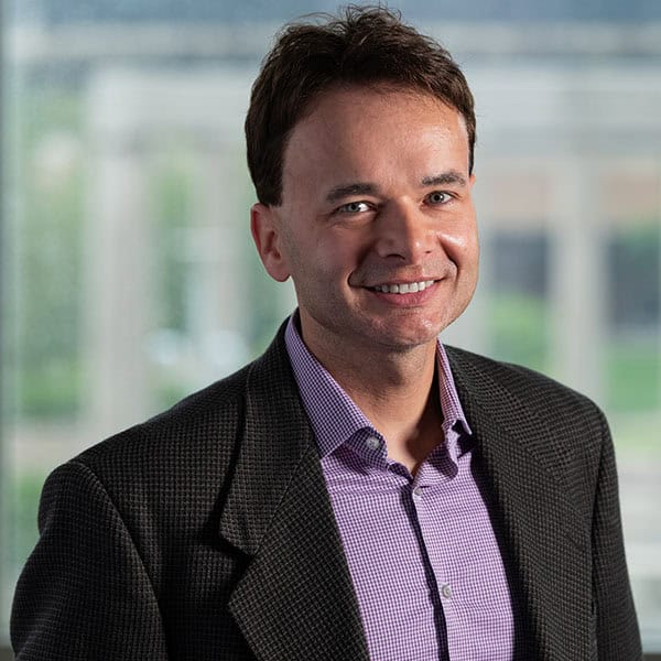 Portrait of a smiling man in a blazer and purple shirt