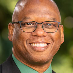 Portrait of a smiling man wearing glasses and a green shirt