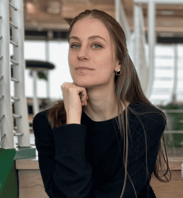 Woman in a black sweater resting her chin on her hand indoors