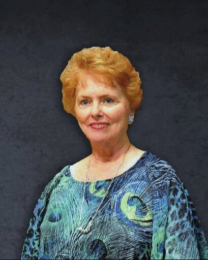 Portrait of a smiling woman with short red hair wearing a blue patterned blouse