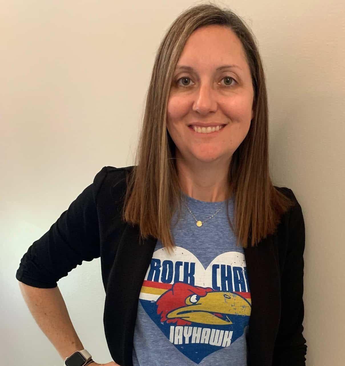Woman smiling in a Rock Chalk Jayhawk T-shirt and black cardigan