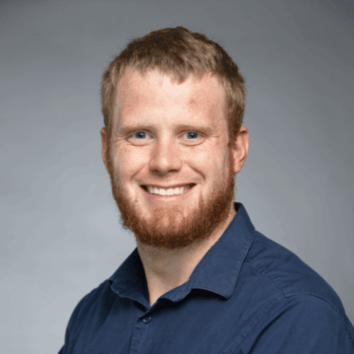 Portrait of a smiling man with a red beard wearing a blue shirt
