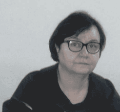 Portrait of a woman with short dark hair and glasses, wearing a dark shirt