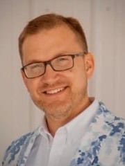 Portrait of a smiling man wearing glasses and a light blue patterned shirt