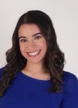 Portrait of a smiling woman with dark hair wearing a blue top