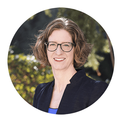 Portrait of a woman wearing glasses and a dark blazer outdoors
