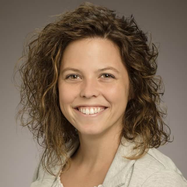 Smiling woman with curly brown hair in a light-colored top