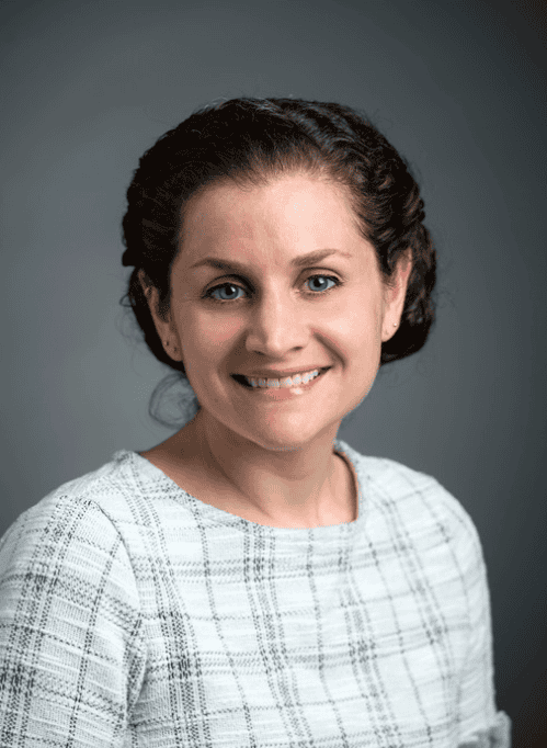 Portrait of a smiling woman in a light plaid top against a gray background
