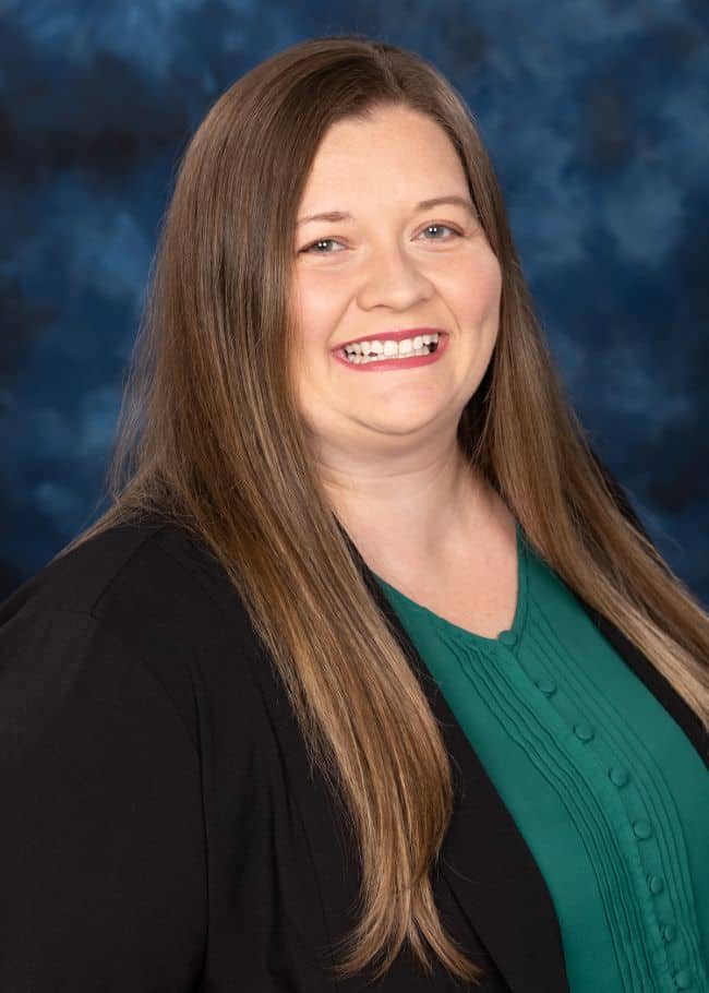 Portrait of a smiling woman with long brown hair against a blue background