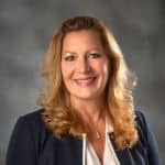 Portrait of a smiling woman with blonde hair in a dark blazer