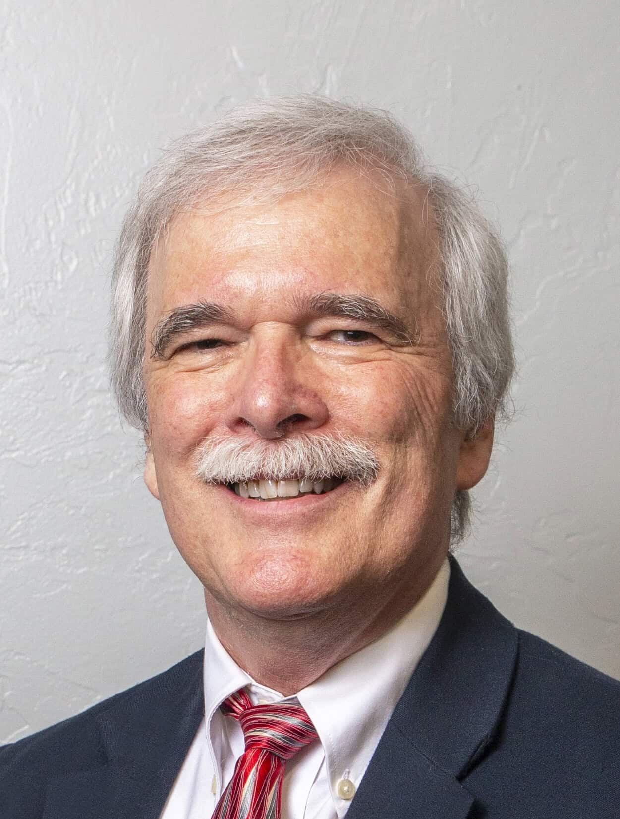 Smiling older man in a suit and red striped tie
