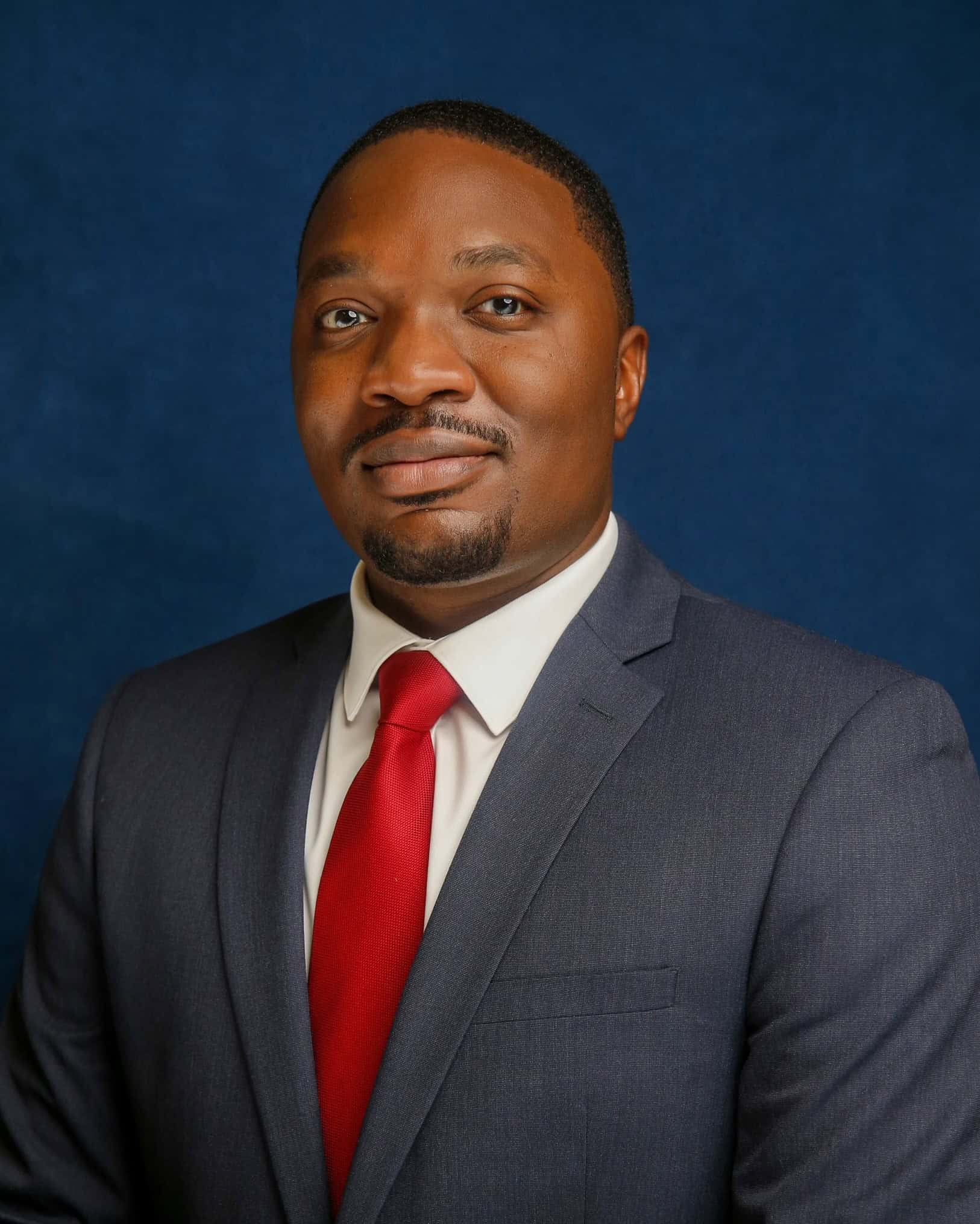 Portrait of a man in a suit and red tie against a blue background