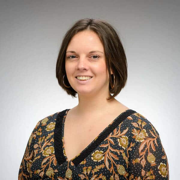 Portrait of a smiling woman with short brown hair wearing a patterned blouse