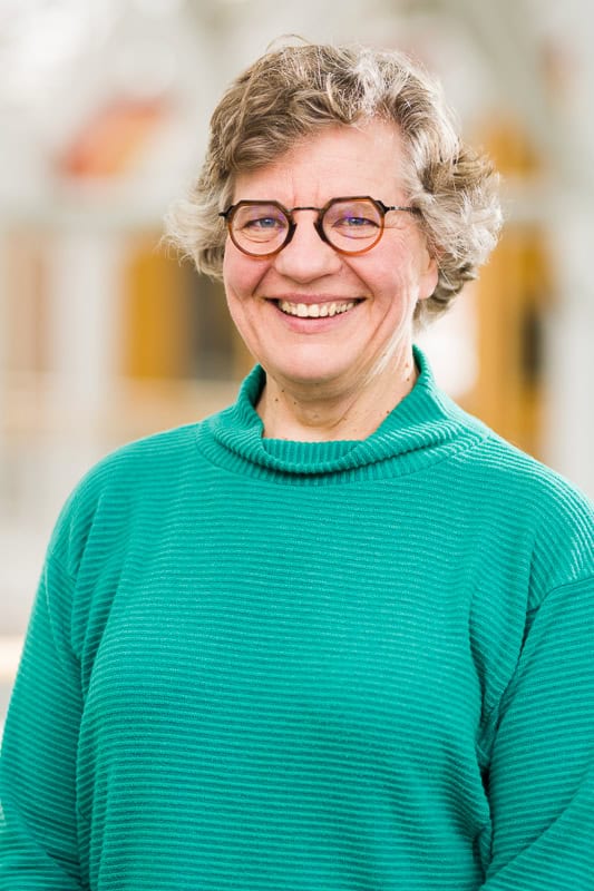 Smiling woman wearing glasses and a teal sweater