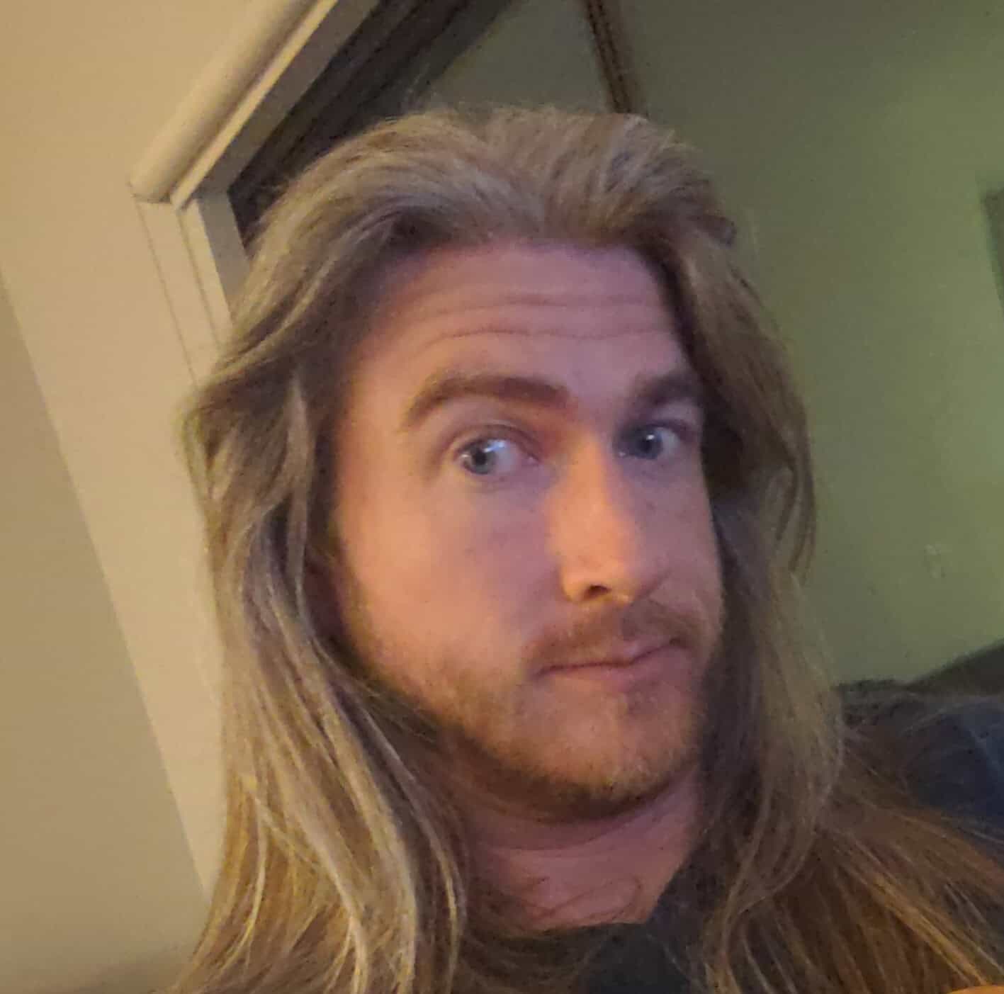 Selfie of a man with long hair and a beard looking at the camera