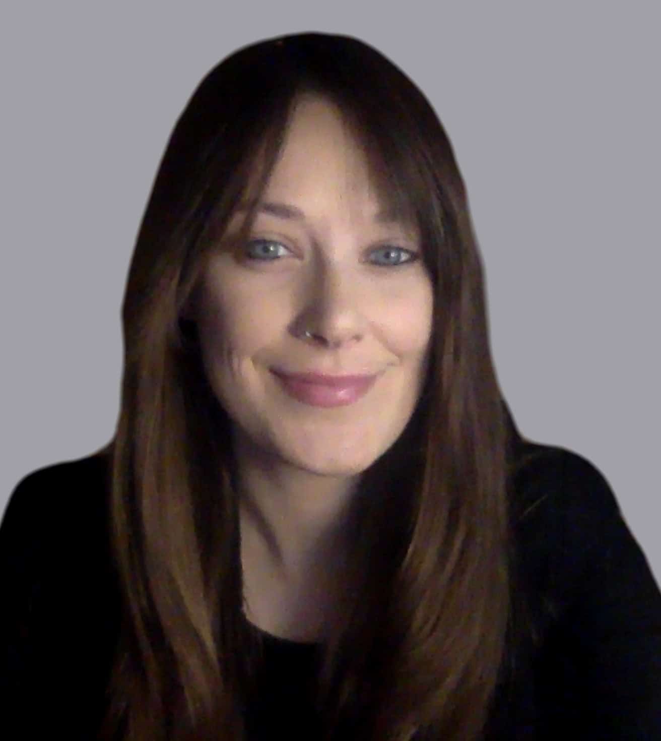 Portrait of a smiling woman with long brown hair on a gray background