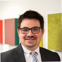Portrait of a man in a suit and glasses standing in front of colorful wall panels
