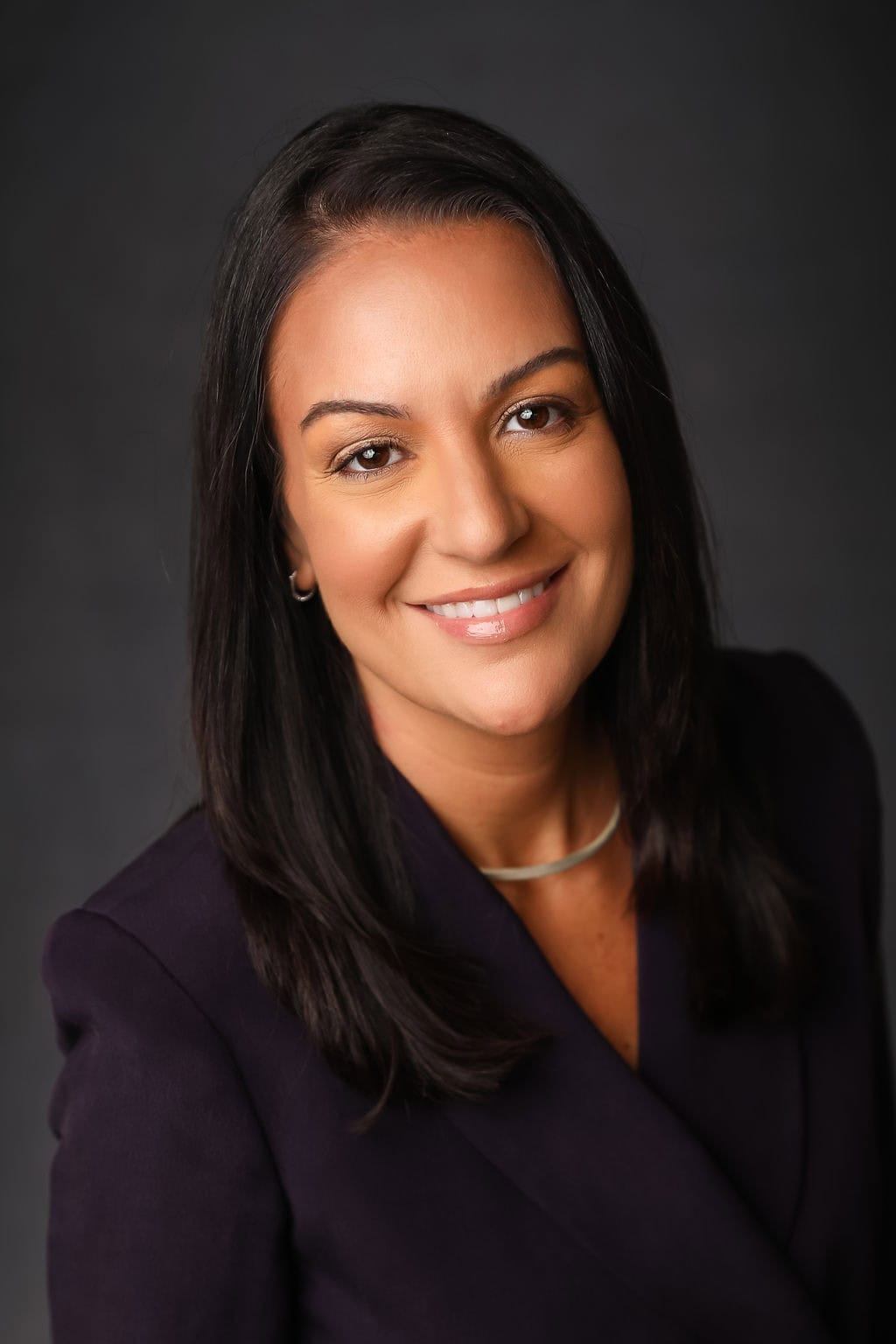 Portrait of a smiling woman with dark hair against a dark background