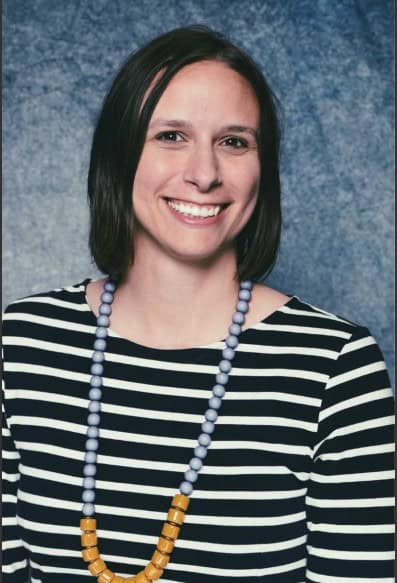 Portrait of a smiling woman wearing a black-and-white striped shirt and beaded necklace