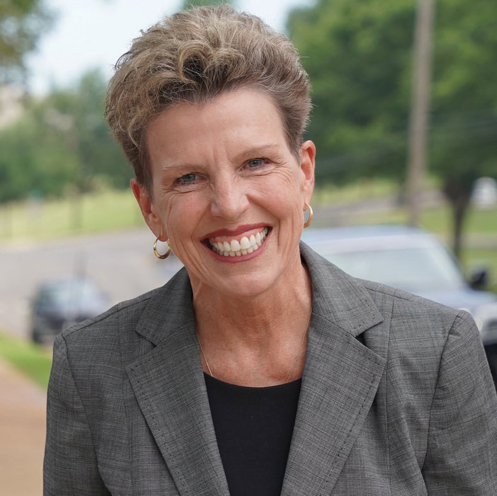 Smiling woman in a gray blazer outdoors