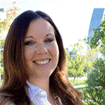 Smiling woman outdoors with trees and a building in the background