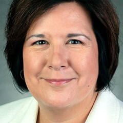 Portrait of a smiling woman with short dark hair and a white collared shirt