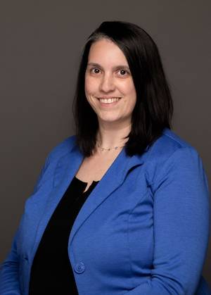 Portrait of a smiling woman in a blue blazer against a gray background
