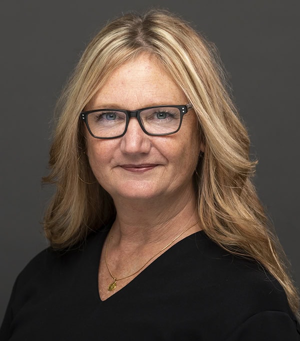 Portrait of a woman with blonde hair and glasses wearing a black top