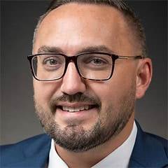 Portrait of a smiling man wearing glasses and a blue suit jacket