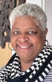 Portrait of a smiling woman with short gray hair wearing a black-and-white patterned scarf