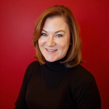 Portrait of a smiling woman in a black turtleneck against a red background