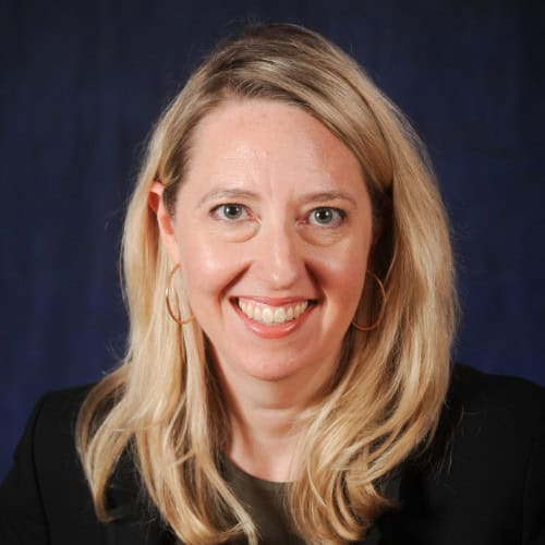 Portrait of a smiling blonde woman against a dark blue background
