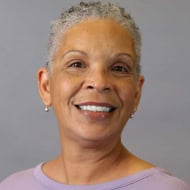 Portrait of a smiling older woman with short gray hair on a gray background