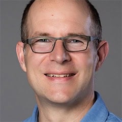 Portrait of a smiling man wearing glasses and a blue shirt