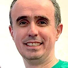 Portrait of a smiling man with a shaved head and green shirt