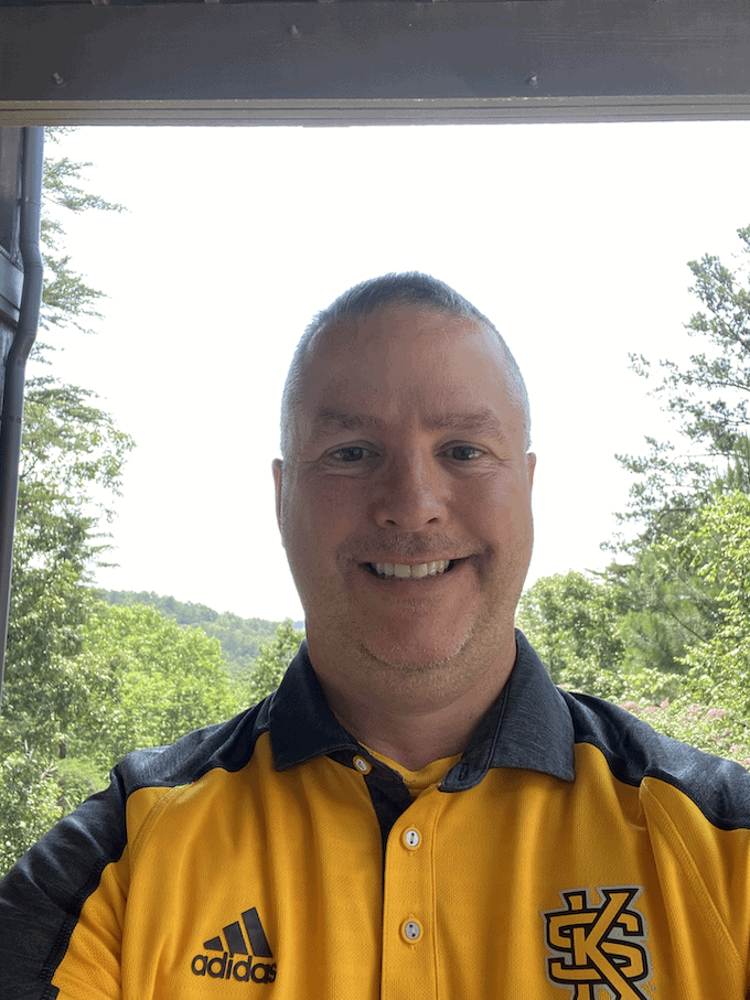 Profile photo of Paul Parker smiling while wearing a yellow Kennesaw State University T-shirt.