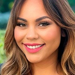 Close-up portrait of a smiling woman with long highlighted hair and pink lipstick