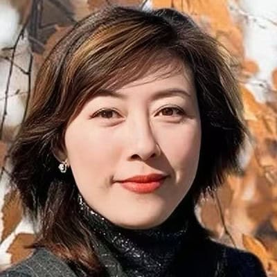 Portrait of a woman with short brown hair and red lipstick, wearing a black turtleneck outdoors