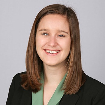 Portrait of a smiling woman in a black blazer and green blouse