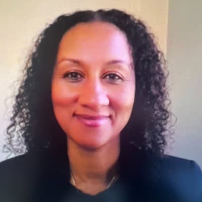 Portrait of a smiling woman with curly hair against a plain background