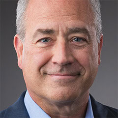 Portrait of a smiling middle-aged man in a suit jacket and blue shirt