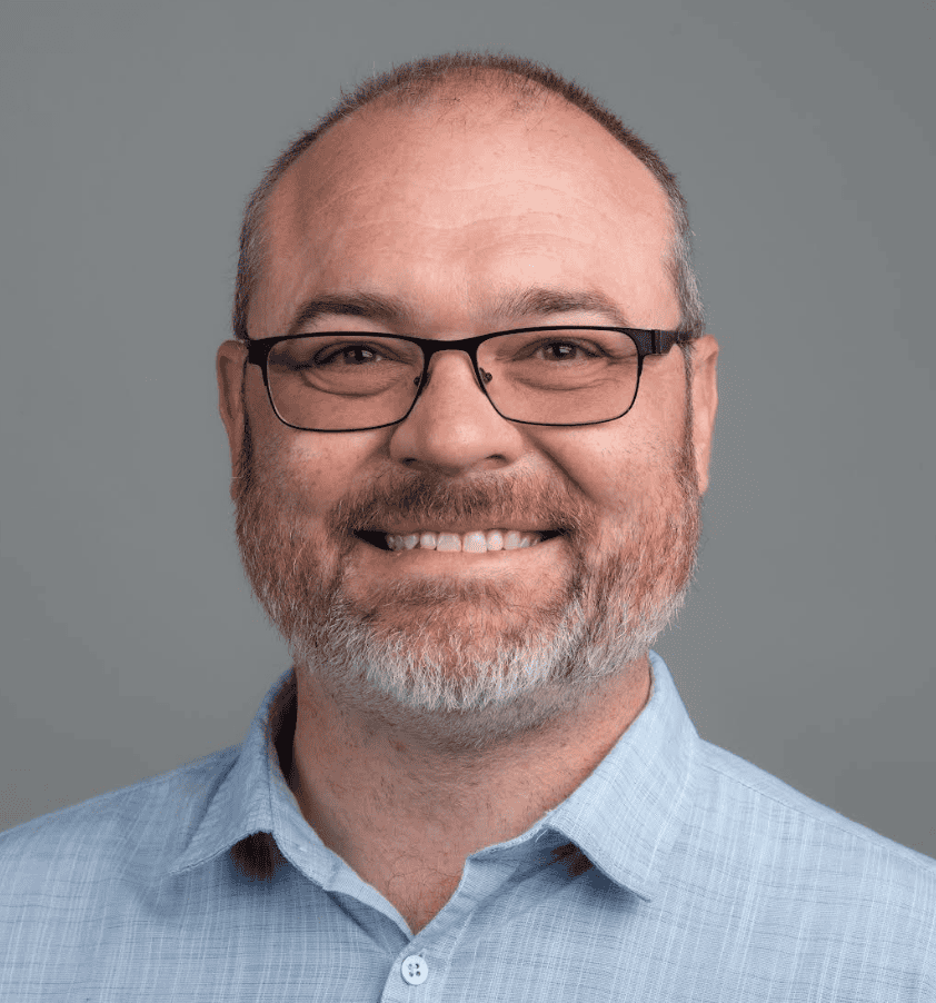 Portrait of a smiling man wearing glasses and a light blue shirt