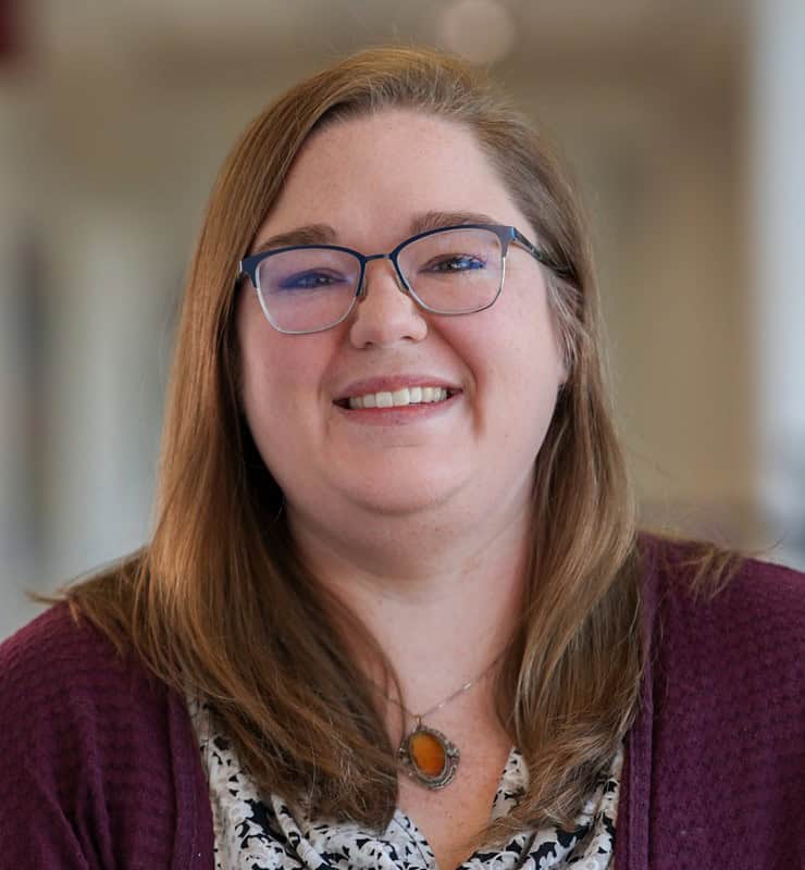Portrait of a smiling woman wearing glasses and a purple sweater