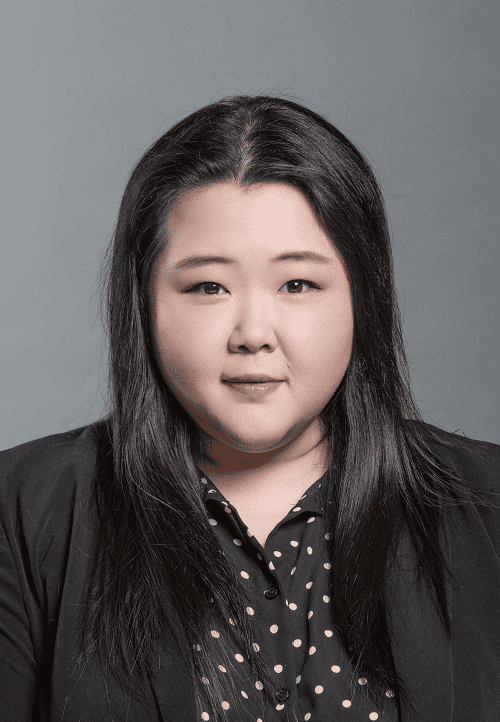 Portrait of a woman with long dark hair wearing a black blazer and polka-dot blouse