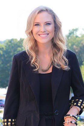 Portrait of a smiling blonde woman wearing a black blazer outdoors