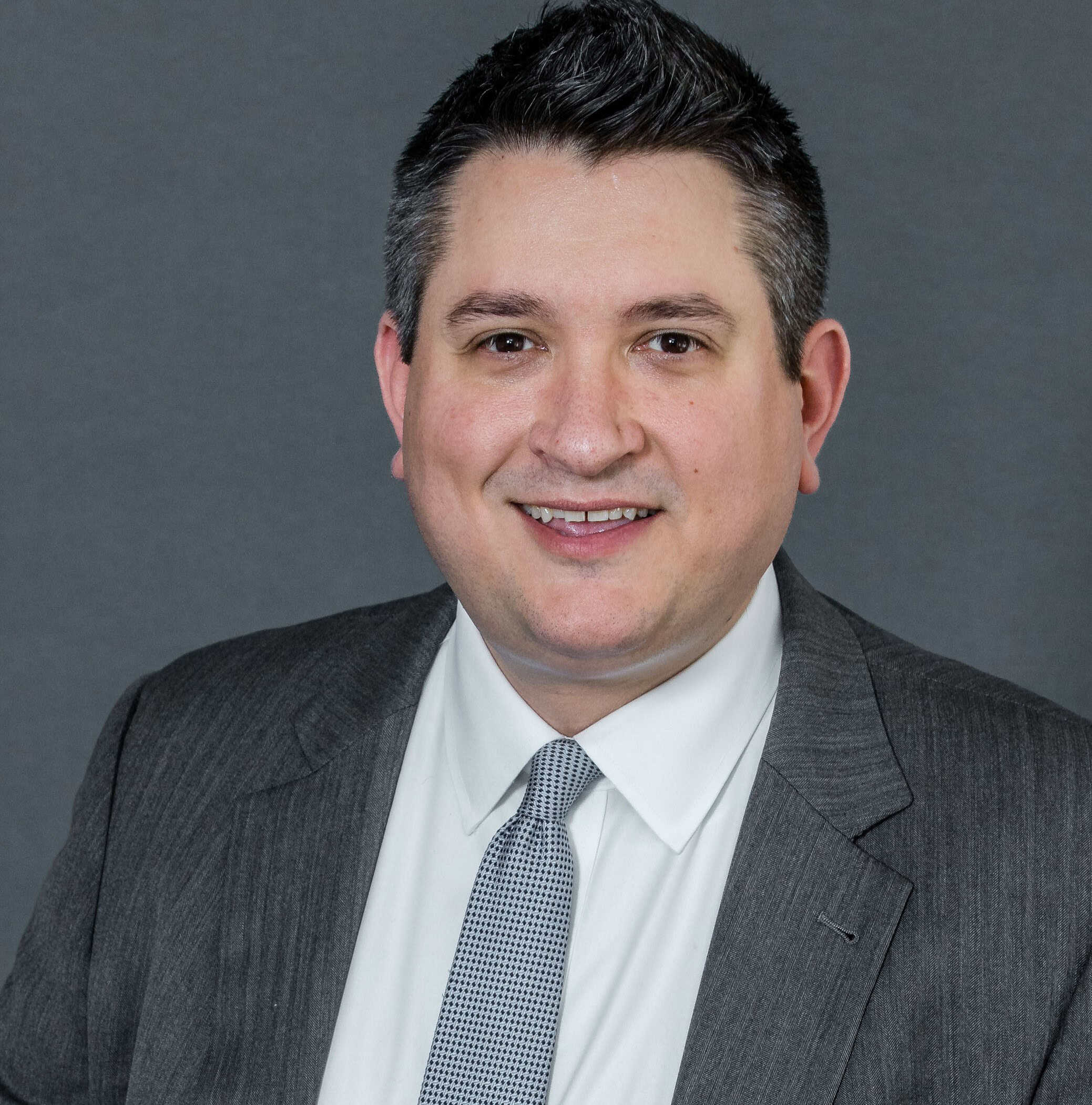 Portrait of a man in a gray suit and tie against a gray background