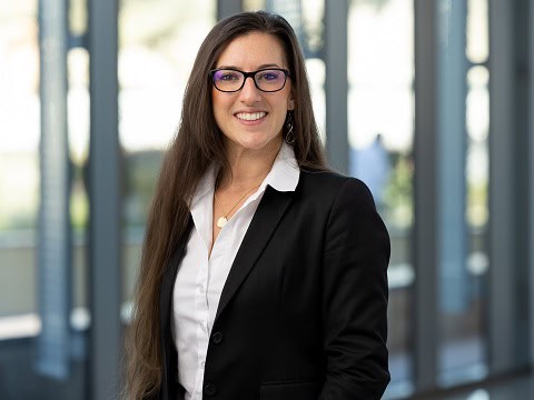 Portrait of a smiling woman in glasses wearing a black blazer and white shirt